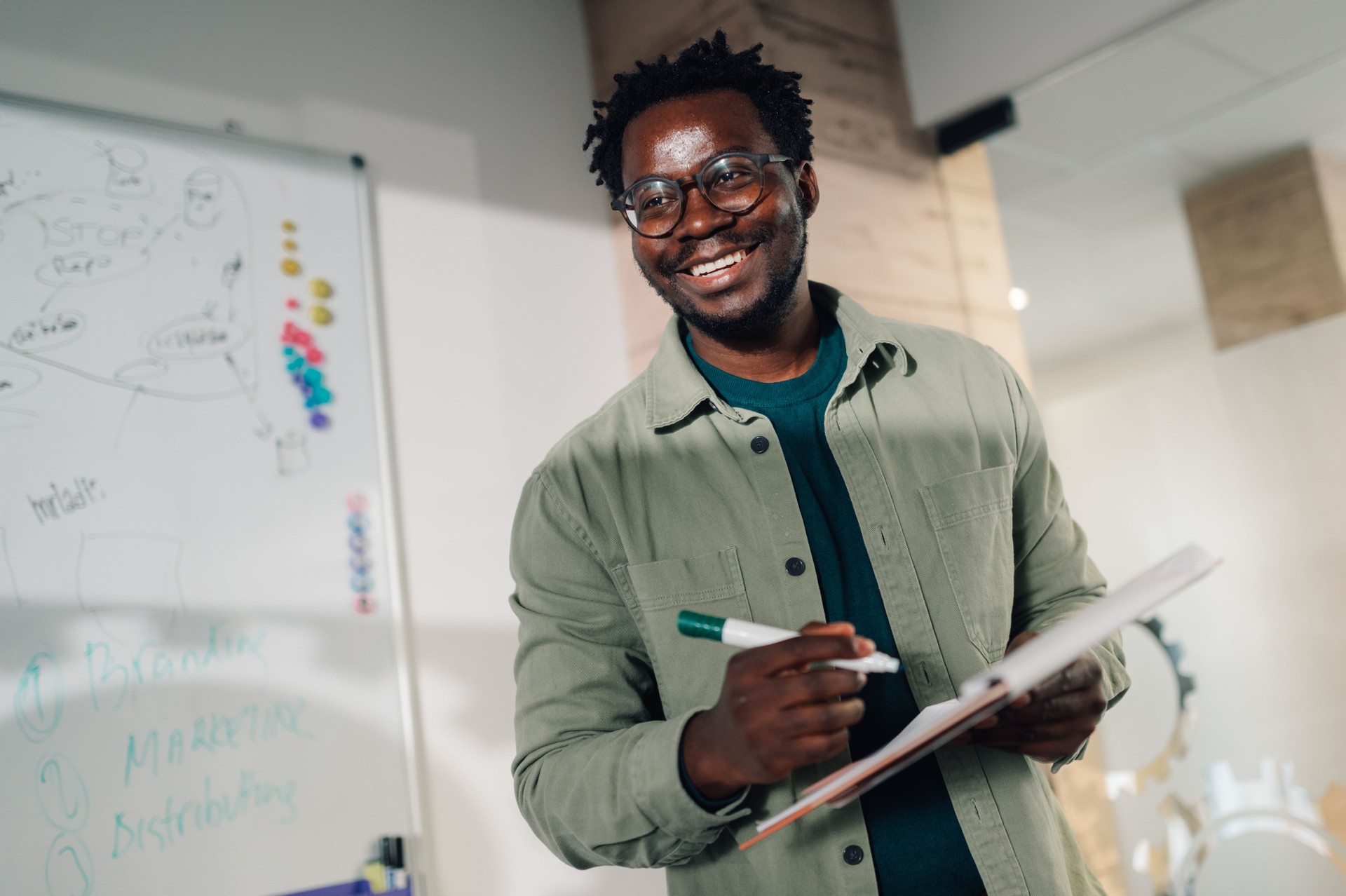 Smiling businessman holding notebook and marker in office meeting room