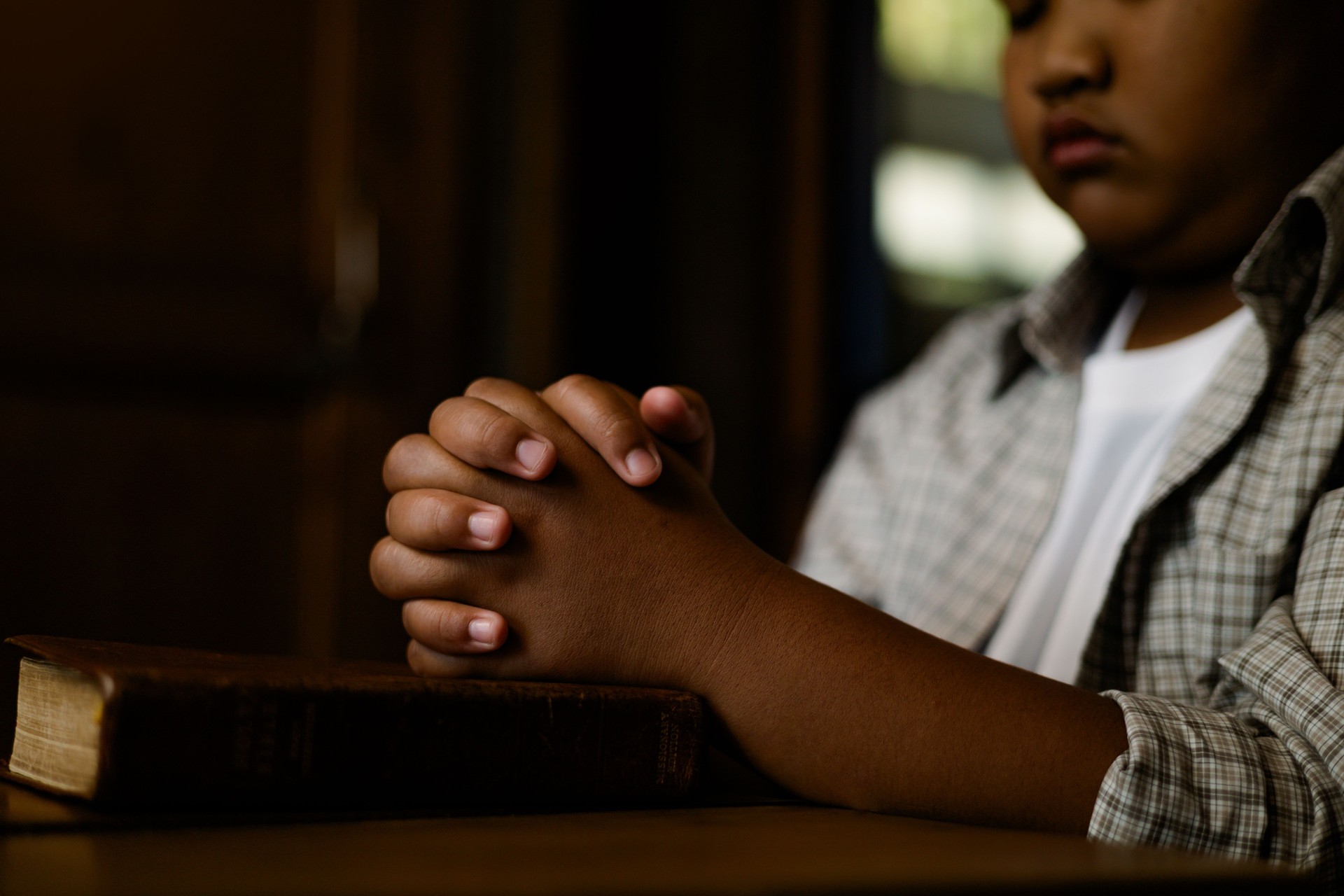 Black boy praying for god on wooden table.